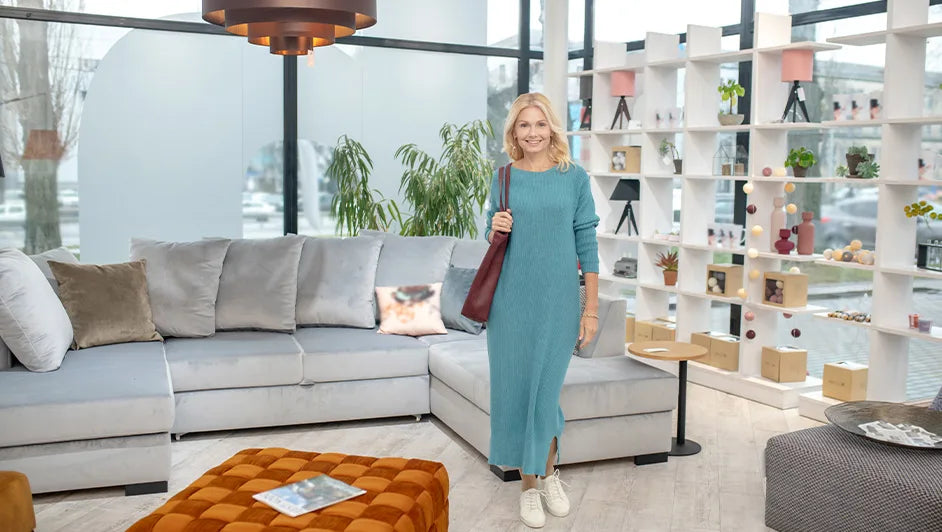 Woman standing in a modern Australian furniture showroom with grey sectional sofa and contemporary décor display