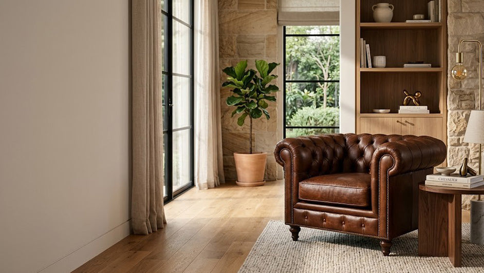 Classic brown leather Chesterfield armchair in a modern living room with timber shelving and large windows