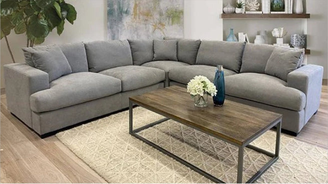large grey modular L-shaped sofa with wood coffee table and patterned rug in modern living room